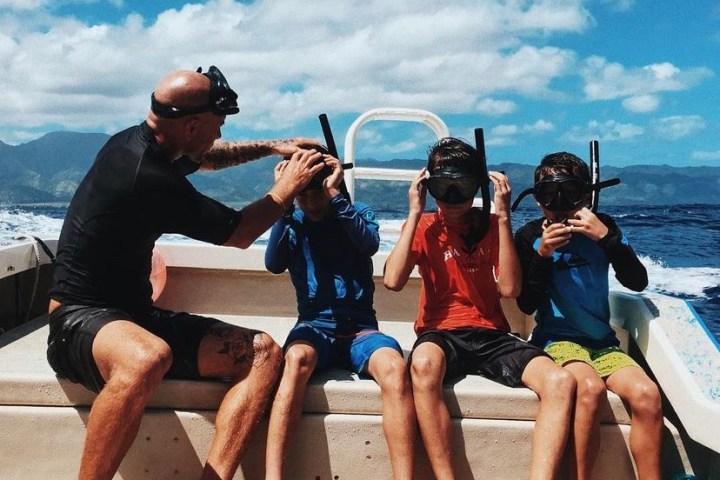 a group of people sitting on a bench next to a body of water