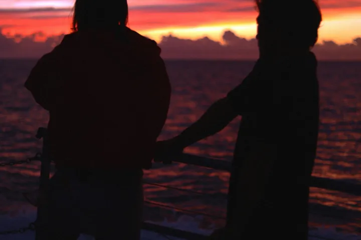 a group of people standing in front of a sunset