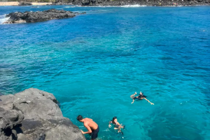 a group of people on a rock next to a body of water
